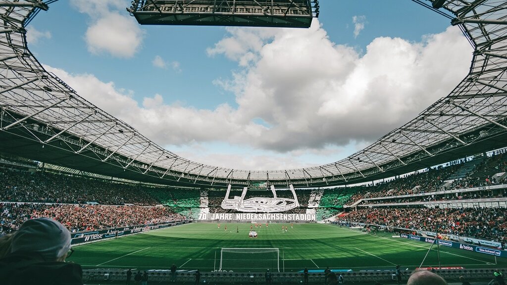 Panoramablick von innen auf ein Fußballstadion mit offenem, rundem Dach.