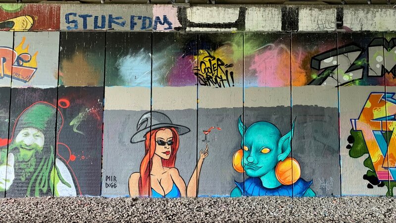 Bunte Sprühkunst auf einer Wand in einer Unterführung.