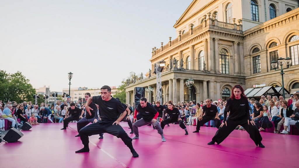Eine Tanzgruppe performt auf einer Bühne vor dem Opernhaus Hannover.